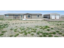 View of the front exterior of the home with a large yard and detached garage at 62681 E Hampden Pl, Byers, CO 80103