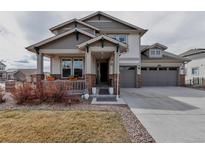Charming two-story home featuring a covered front porch and a three-car garage at 8255 S Vandriver Way, Aurora, CO 80016