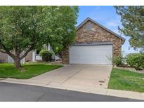 Charming home featuring a stone-accented two-car garage and a well-manicured front yard with mature trees at 12277 W Chenango Dr, Morrison, CO 80465