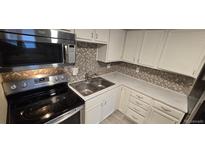 Well-lit kitchen with stainless steel appliances, white cabinetry, and decorative backsplash at 8828 E Florida, Denver, CO 80247