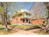 Charming brick home with a white-columned porch and well-maintained landscaping at 3905 Tejon St, Denver, CO 80211