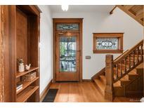 Charming foyer with hardwood floors, built-in shelving, and stained glass window accents by the front door and staircase at 3905 Tejon St, Denver, CO 80211