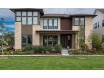 Modern two-story home featuring a stone facade, large windows, well-manicured lawn, and professional landscaping at 5866 Boston Ct, Denver, CO 80238