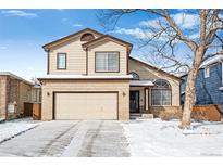 Charming two-story home featuring a two-car garage and landscaped yard during winter at 9421 Morning Glory Ln, Highlands Ranch, CO 80130