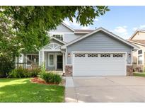Charming two-story home with a two-car garage, a covered porch, and manicured lawn and flower beds at 19135 E Hickock Dr, Parker, CO 80134