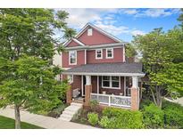 Charming two-story home with red siding, a covered front porch, and lush landscaping at 2908 N Florence St, Denver, CO 80238