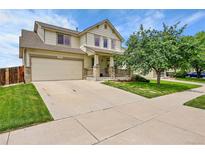 Charming two-story home with a well-maintained lawn, covered porch, attached two-car garage and concrete driveway at 11285 Iola St, Commerce City, CO 80640