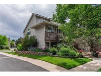 Charming two-story home with a wooden porch and lush landscaping surrounding the walkway at 1470 S Quebec Way # 245, Denver, CO 80231