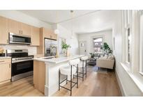 Open concept kitchen flows into the living room with stainless appliances, light wood cabinets, and a stylish island at 1470 Knox Ct, Denver, CO 80204