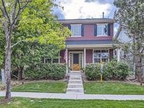 Charming two-story home with manicured lawn, mature trees, and inviting front porch at 8367 Devinney St, Arvada, CO 80005