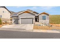 Charming single-Gathering home featuring a three-car garage, stone accents, and xeriscaped front yard at 4706 Mesa Top Dr, Monument, CO 80132