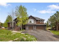 Two-story house with a two-car garage, natural landscaping, and a basketball hoop at 1654 Muirfield Ln, Evergreen, CO 80439
