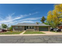 Charming single-story brick home featuring an attached garage, well-maintained lawn, and mature trees in a suburban setting at 201 S Monmouth Ave, Firestone, CO 80520