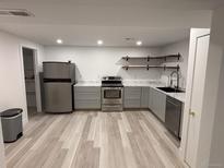 Bright kitchen featuring stainless appliances, gray cabinets and shelving at 201 S Monmouth Ave, Firestone, CO 80520