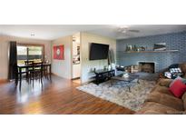 Open living room with wood floors, brick fireplace, and access to kitchen and dining area at 201 S Monmouth Ave, Firestone, CO 80520