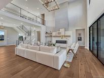 Bright living room boasts hardwood floors, a fireplace, and a soaring ceiling with a modern light fixture at 2690 Fox View Trl, Franktown, CO 80116