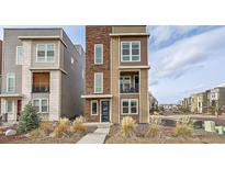 Modern three-story home with stone accents, a small balcony, and manicured landscaping in a vibrant neighborhood at 3574 Corsica Way, Castle Rock, CO 80109