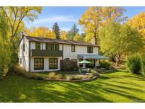 Charming two-story home with a lush green lawn, mature trees, and patio seating area perfect for outdoor entertaining at 6 Martin Ln, Englewood, CO 80113