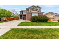 Charming two-story home with a well-manicured lawn, mature trees, and brick and siding exterior at 4873 S Fultondale Way, Aurora, CO 80016