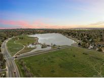 Stunning aerial view of a community lake and green space at sunset, showcasing the surrounding neighborhood at 6402 W 81St Ave, Arvada, CO 80003