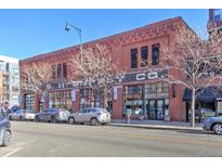 A sunny, street-level view of the commercial building's brick facade, featuring large windows and street parking at 1732 Wazee St # 201, Denver, CO 80202