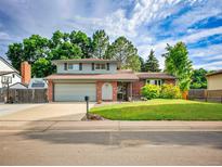 Charming two-story home with a lush green lawn, brick accents, and an attached two-car garage at 4720 W Stanford Ave, Denver, CO 80236