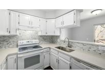 Well-lit kitchen features white cabinetry, quartz countertops, stainless steel sink, and patterned backsplash at 2927 W 81St Ave # B, Westminster, CO 80031