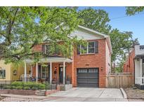 Beautiful two-story red brick home with a well-manicured lawn, front porch, and attached garage at 2436 W Argyle Pl, Denver, CO 80211