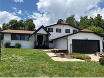Charming two-story home featuring black and white accents, a well-manicured lawn, and a black two car garage door at 8249 Zephyr St, Arvada, CO 80005