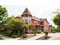 Charming red townhome features unique architectural details, lush landscaping, and inviting curb appeal at 7777 E 23Rd Ave # 1202, Denver, CO 80238
