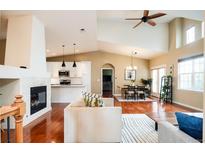 Open-concept living area with vaulted ceilings, fireplace, hardwood floors, and seamless flow to the dining and kitchen at 7777 E 23Rd Ave # 1202, Denver, CO 80238
