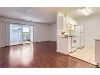 Bright living room featuring hardwood floors, a balcony and open access to a kitchen with white cabinetry at 10762 E Exposition Ave # 336, Aurora, CO 80012