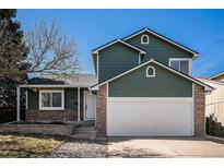 Two story home featuring a two car garage, green siding, brick accents, and manicured front yard at 4871 S Dunkirk Way, Centennial, CO 80015