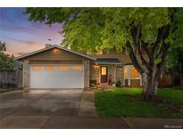 Charming two-story home featuring a brick and wood facade, mature tree, and a two-car garage at 10450 Iris Way, Broomfield, CO 80021