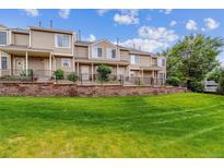 Inviting townhomes with manicured lawn, brick retaining wall, and black metal fencing at 1818 S Quebec Way # 4, Denver, CO 80231