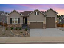 Beautiful home exterior featuring a manicured yard, stone accents, and a three-car garage at 6725 Mentha Dr, Castle Rock, CO 80108