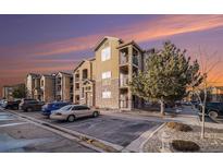 View of the apartments with stone accents, balconies, and ample parking space at dusk at 17525 Wilde Ave # 307, Parker, CO 80134