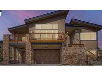 Beautiful modern home with wood and stone elements, a two car garage, and a deck at 5721 Country Club Dr, Larkspur, CO 80118