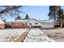 Brick ranch home with attached garage, snowy yard, and walkway at 420 Racine St, Aurora, CO 80011