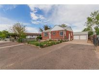 Charming brick home with a well-maintained lawn, long driveway, and detached garage at 8110 Ivy St, Commerce City, CO 80022