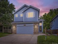 Charming two-story home featuring blue siding, brick accents, and a well-manicured front yard at twilight at 6447 St Vrain Ranch Blvd, Longmont, CO 80504