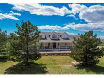 Charming yellow home with a covered porch, dormer windows, and a well-manicured lawn at 895 Antelope W Dr, Bennett, CO 80102