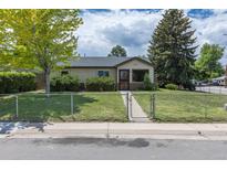 Charming single-story home with chain fence, manicured lawn, and mature trees at 1099 Wheeling St, Aurora, CO 80011