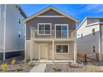 Two-story townhome with balcony, light beige and brown siding, and small front yard at 45036 Sunflower Ln, Bennett, CO 80102