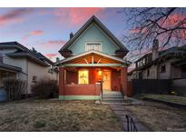 Charming red brick home featuring a covered porch, flowering hanging baskets, and inviting front steps at dusk at 2945 Grove St, Denver, CO 80211