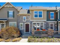 Charming townhome featuring stone accents and a cozy front porch with decorative flower pots at 835 Stony Mesa Pl, Castle Rock, CO 80108