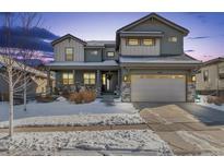 Two-story house with a gray exterior, stone accents, and a three-car garage in winter at 16382 Spanish Peak Way, Broomfield, CO 80023