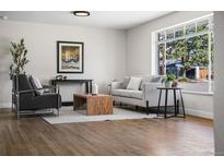 Bright living room featuring hardwood floors, modern furniture, and a large window with a neighborhood view at 6923 S Albion St, Centennial, CO 80122