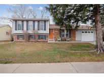 Split-level home featuring a well-maintained front yard and classic brick and siding exterior with attached garage at 8548 W Dartmouth Pl, Lakewood, CO 80227