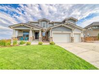 Two-story home with three-car garage, stone accents, and manicured lawn at 16272 W 95Th Ln, Arvada, CO 80007